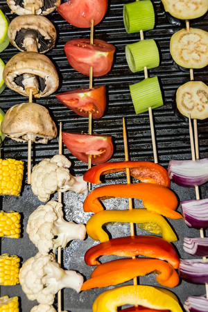 vegetarian barbecue a lot of different vegetables corn mushrooms pepper sprouts mushrooms tomatoes zucchini eggplant kebab on skewers on a plateの写真素材