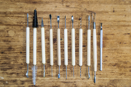 Tools for working with clay modeling on a wooden background
