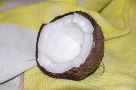 Cracked half coconut on a yellow tablecloth
