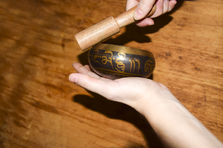 Brass singing Tibetan spiritual bowl  on a wooden background healing sound and handの写真素材