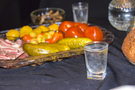 Tsarist still life luxury decanter of vodka and appetizer lard pickled cucumbers tomatoes pepper mushrooms black bread on a black background crumbs
Â の写真素材