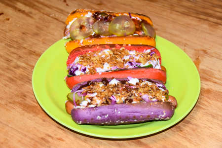 hot dogs assorted multi-colored buns different toppings on a wooden backgroundの写真素材