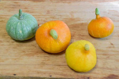 several orange and one green fresh pumpkins lie on a wooden backgroundの写真素材