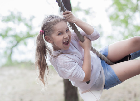Cute girl on a rope swing at the sea coastの写真素材