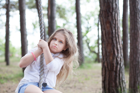 Cute girl on a rope swing at the sea coastの写真素材