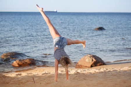 Young lady do exercises at the sea cost