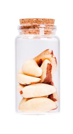 Brazil nuts in a glass bottle with cork stopper, isolated on white.の写真素材