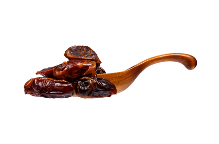 Dates in the wooden spoon, isolated on white background.の写真素材