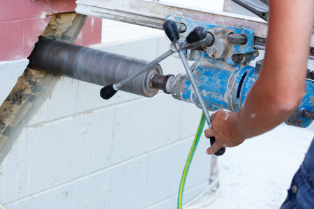 Worker drilling holes in concrete floor at construction site.の写真素材