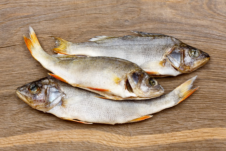 Three dried fishes on a vintage wooden bacground.の写真素材