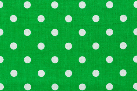 Close up of green fabric with white polka dots