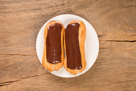 Freshly baked chocolate eclairs on white plate, top view. Traditional French dessert.の写真素材