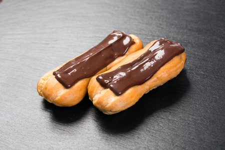 Close up of chocolate eclairs on black background.