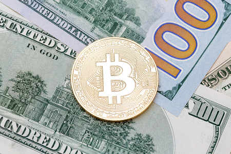 Golden cryptocurrency bitcoin on US bank notes. High resolution photo.