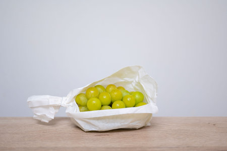 Grapes in a paper bag on a wooden table and white background