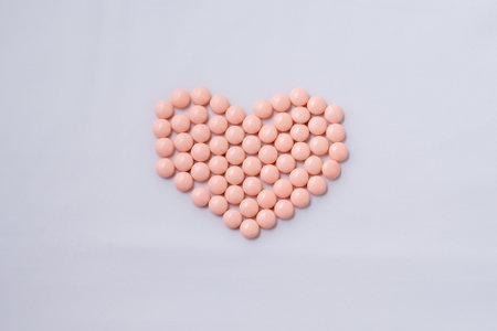 Pink pills in shape of heart on white background. Copy space.の写真素材