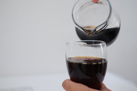 Pouring cola from a jug into a glass on a white backgroundの写真素材