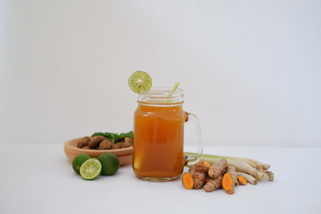 ginger tea in a glass with lime and ginger root on white background