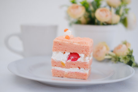 Strawberry cake on white dish with coffee cup and vaseの写真素材