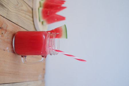 Watermelon smoothie in a glass jar with a straw on a white backgroundの写真素材