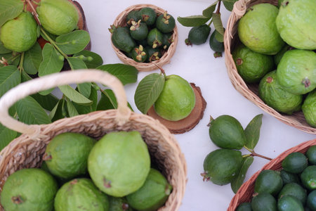Fresh guava and feijoa fruit in basket with green leavesの写真素材