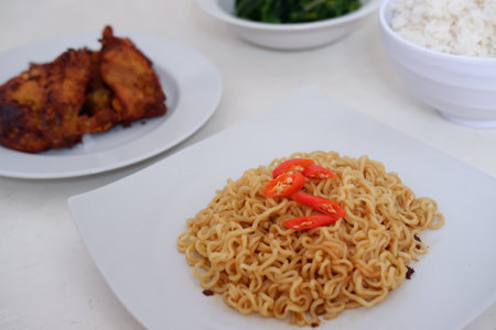 instant noodle on white plate with hot chilli and fried chickenの写真素材