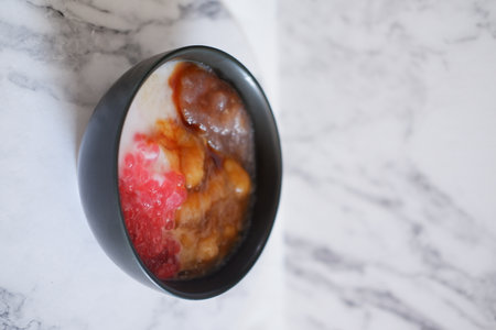 Strawberry and strawberry yogurt in a black cup on a marble backgroundの写真素材