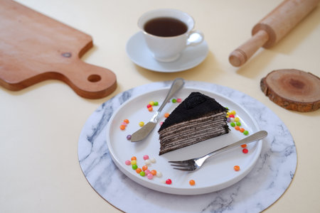 A piece of chocolate cake on a white plate and a cup of coffee