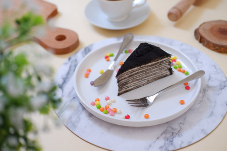Chocolate cake on a white plate with spoon and fork on the tableの写真素材