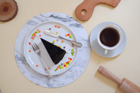 Cup of tea and chocolate cake on a white plate on a beige backgroundの写真素材