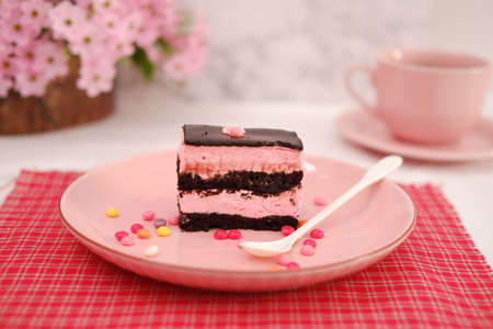 Piece of chocolate cake on a pink plate with a cup of coffee