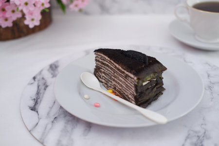 Piece of homemade chocolate crepes cake on a white plate