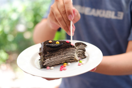 Piece of homemade chocolate crepes cake on a white plate