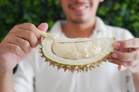 Close up of young man holding durian fruit in his hand.の写真素材
