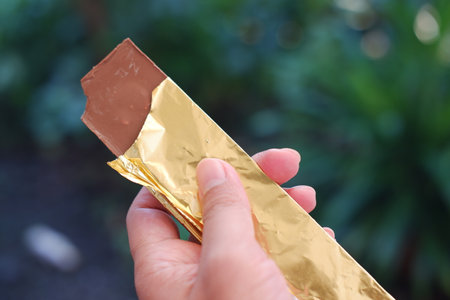 Hand holding a chocolate bar in the garden. Selective focus.の写真素材