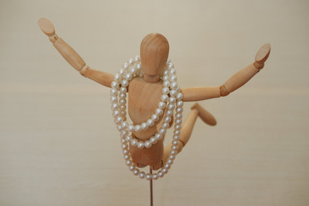 Wooden mannequin with pearls on a wooden background.の写真素材