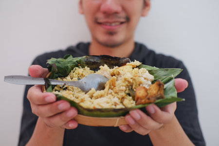 Asian man holding a plate of rice with chicken and vegetableの写真素材