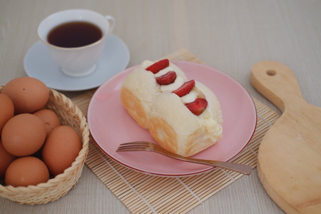 Strawberry cheese cake with cup of coffee on wooden table.
