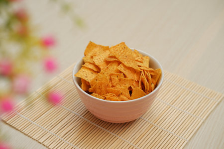 Nachos chips in a bowl on a bamboo placematの写真素材