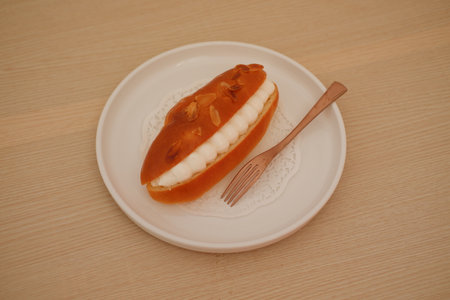Eclair on a white plate with wooden background, top view.の写真素材