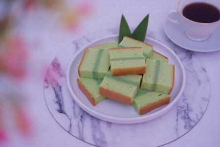 pandan cake on a white plate with cup of teaの写真素材