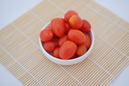 cherry tomatoes in a bowl on a bamboo matの写真素材