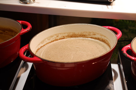 red pot filled with a creamy soup or sauce, sitting on a stovetopの写真素材