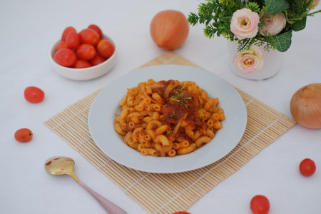 Macaroni with tomato sauce and onions on a white plate.の写真素材
