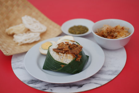 rice with meat, egg, crackers, sambal and noodles on a red backgroundの写真素材