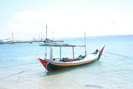 Quiet Beach with Traditional Boat and Clear Blue Watersの写真素材