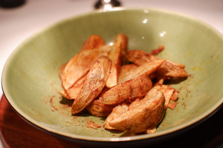 Fried potatoes in a green plate on a wooden tableの写真素材
