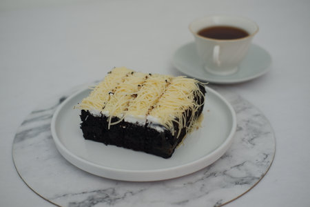 A piece of black cake topped with shredded cheeseの写真素材