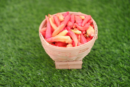 Red and yellow chilli in basket on green grassの写真素材
