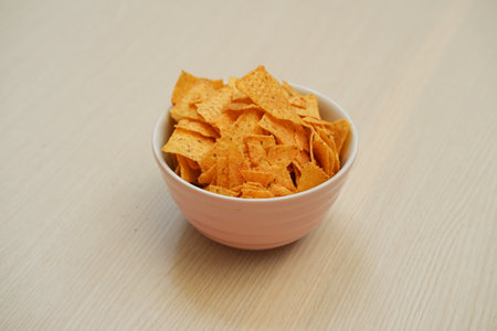 Nachos chips in a white bowl on a wooden tableの写真素材